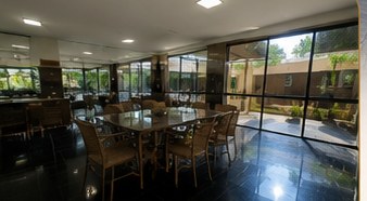 Refeitório amplo com mesas e vista para o jardim